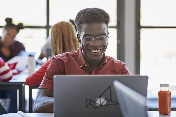 Young student wearing eyeglasses while using laptop