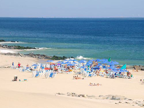 A cluster of blue umbrellas line the beach at Long Branch