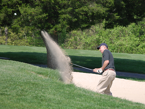 A golfer sprays sand as he swings his way out of a bunker at the Spring Meadow Golf Course near Farmingdale