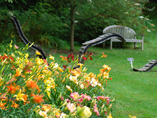 Area containing a bed of flowers and wood sculptures 