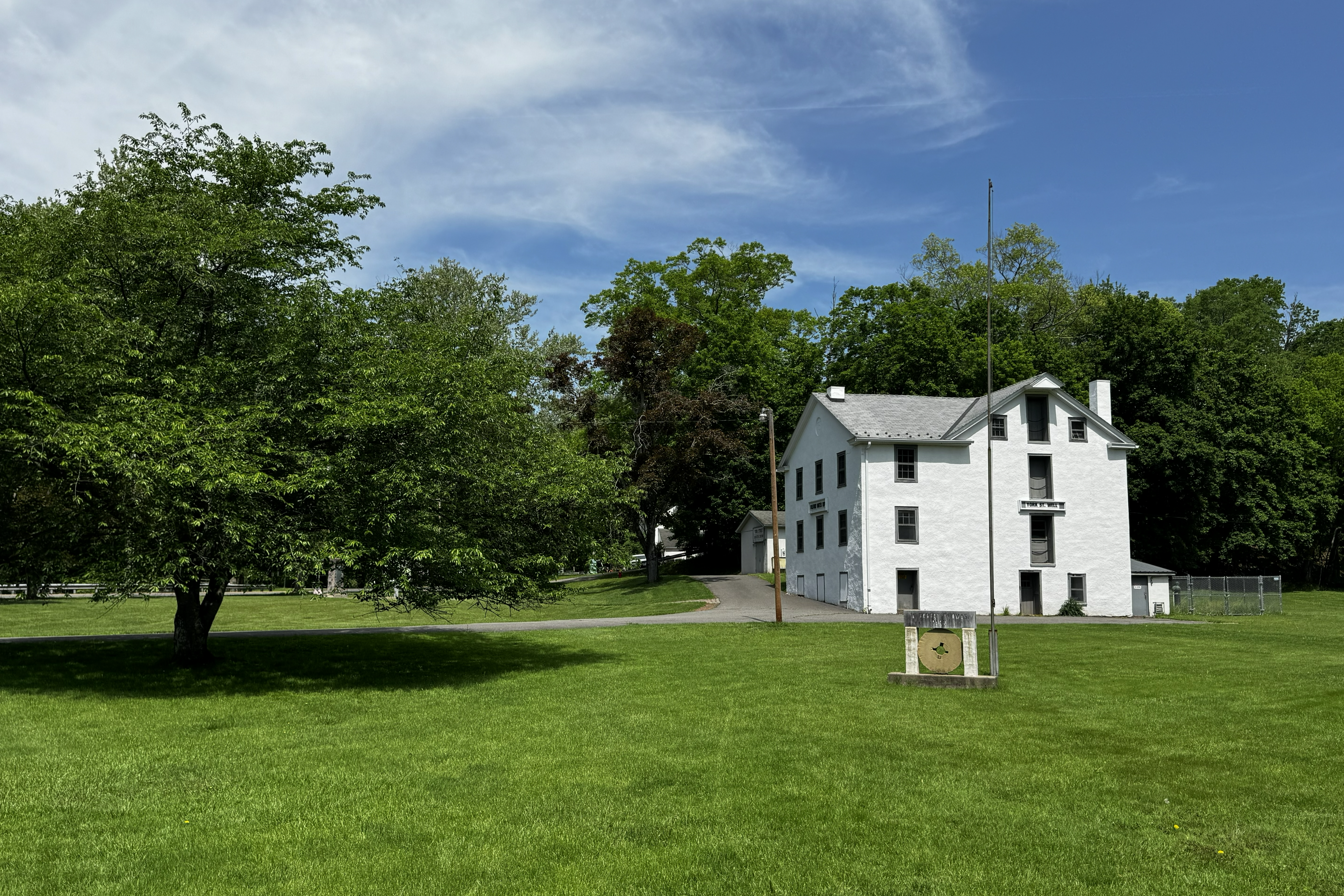 a field, a tree and a white building