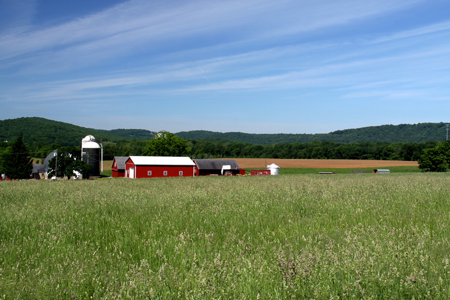 farm field red barn in distance. hills.