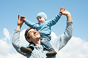 Photo of a father with his son on his shoulders