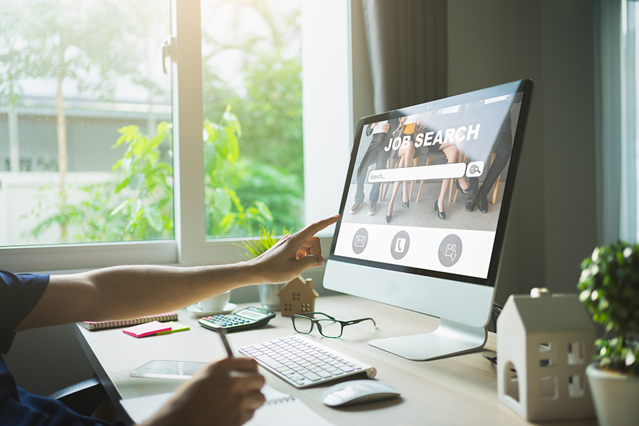 A person looking for jobs online at a computer monitor