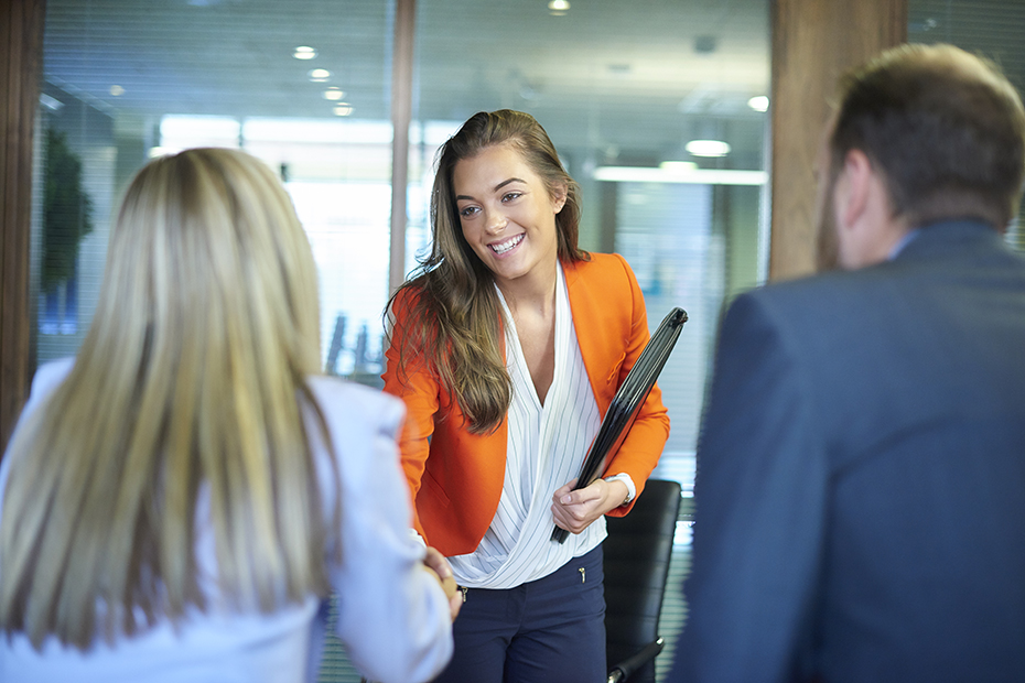 Interviewee smiling and shaking the hand of an interviewer