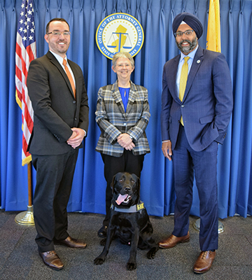 Left to right: Investigator Joseph Sczerbowicz, Racing Commission Executive Director Judy Nason and Attorney General Gurbir S. Grewal with Shadow, the Racing Commission’s trained, scent-sniffing dog.