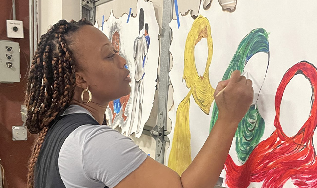 A woman painting on paper taped to the inside of a garage door