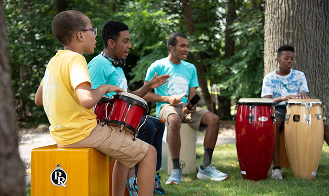 three young men play music in an outdoor setting